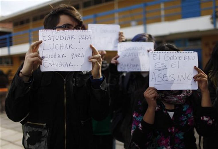 Students hold up signs that read in Spanish \"Study to fight...fight to study...,\" left, and \"The government is the assassin\" inside a high school where five students are on hunger strike in Buin, Chile, Tuesday, Aug. 23, 2011. Chile's largest union coalition, representing about 13 percent of the work force and many government employees, are calling for a strike for Wednesday and Thursday to join forces with high school and university students who have boycotted classes for three months now.  They want to replace Chile's dictatorship-era constitution, which concentrates vast power in the presidency, with a new charter that enables popular referendums and makes free education a right for all citizens. They also want pension reforms, a new labor code and more investments in health care. (AP Photo/Roberto Candia)